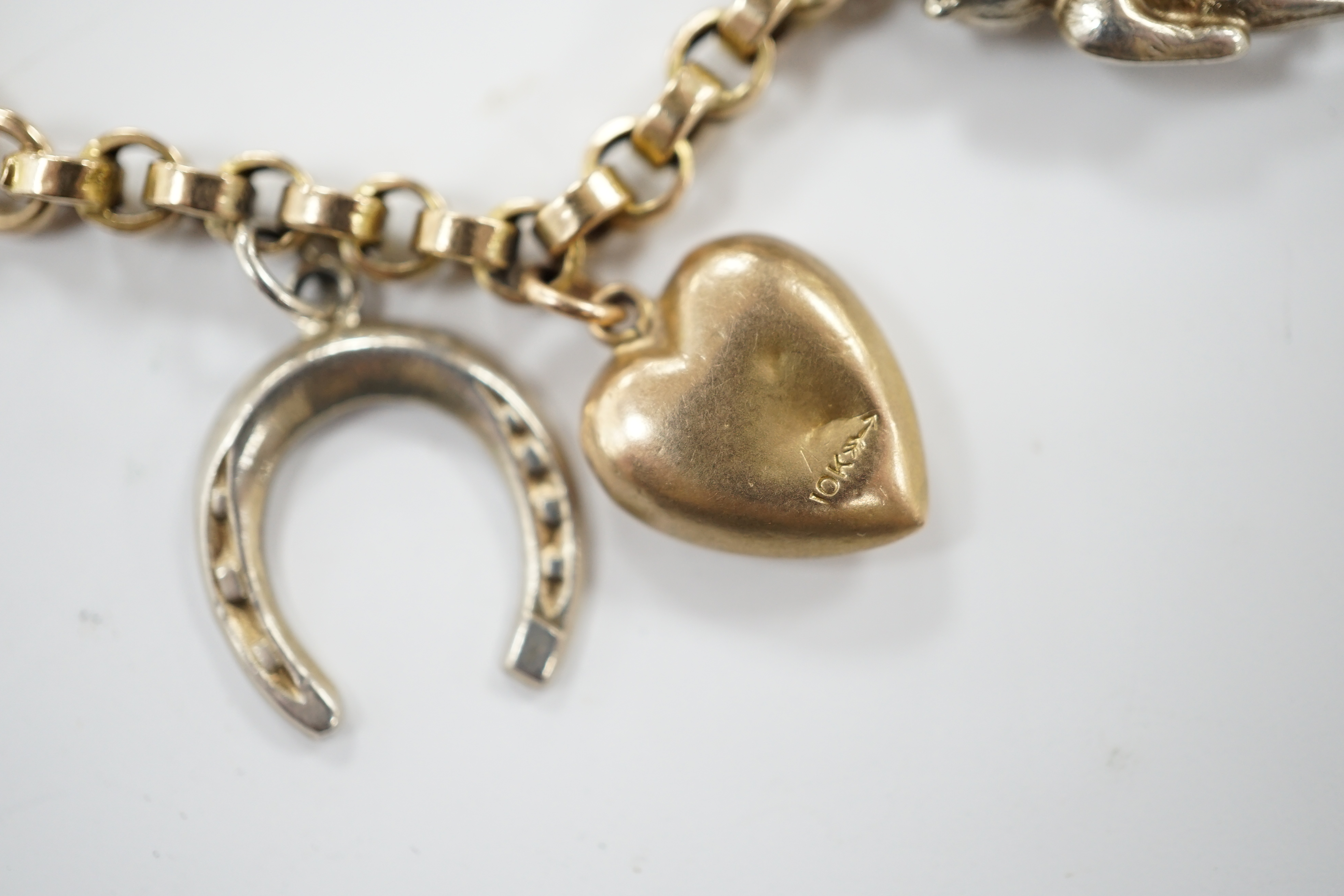 A 9ct charm bracelet, hung with nine assorted yellow and white metal charms including sterling and 10k, 16cm